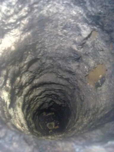 View down a flue coated in tar deposits before reaming