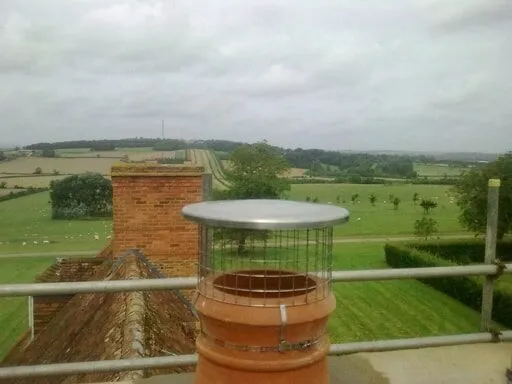 New cowl fitted to a chimney pot, overlooking open countryside