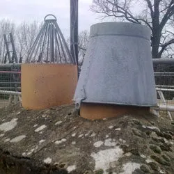 Old chimney pots, one capped, on a weathered stack before restoration