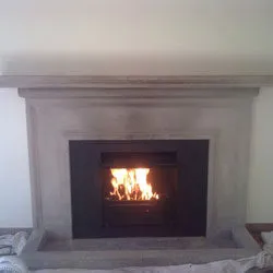 Lit stove in a fireplace with a new stone surround