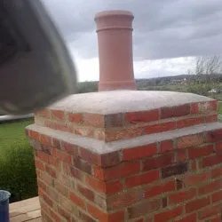 Rebuilt brick chimney stack with a single terracotta pot
