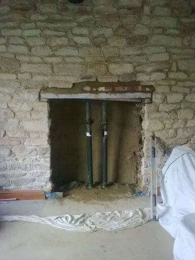 Fireplace opening in a stone wall prepared for a stove, with the flue liner in place