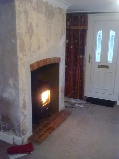 Lit stove in a brick-lined fireplace near a front door