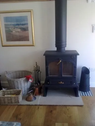 Freestanding wood burning stove with its flue pipe, on a tiled hearth